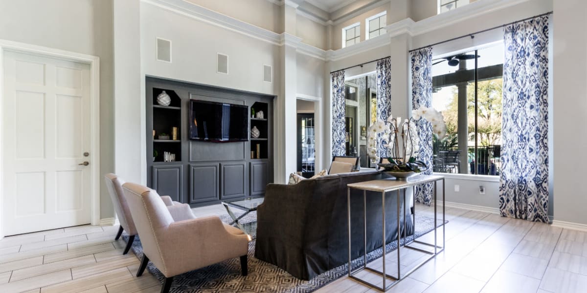 Lobby and clubhouse main indoor entrance sitting area with large screen television at Marquis at Stonegate in Fort Worth, Texas