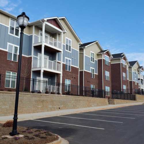 Exterior view of the apartment building with parking at Groves at Peach Orchard in Belmont, North Carolina