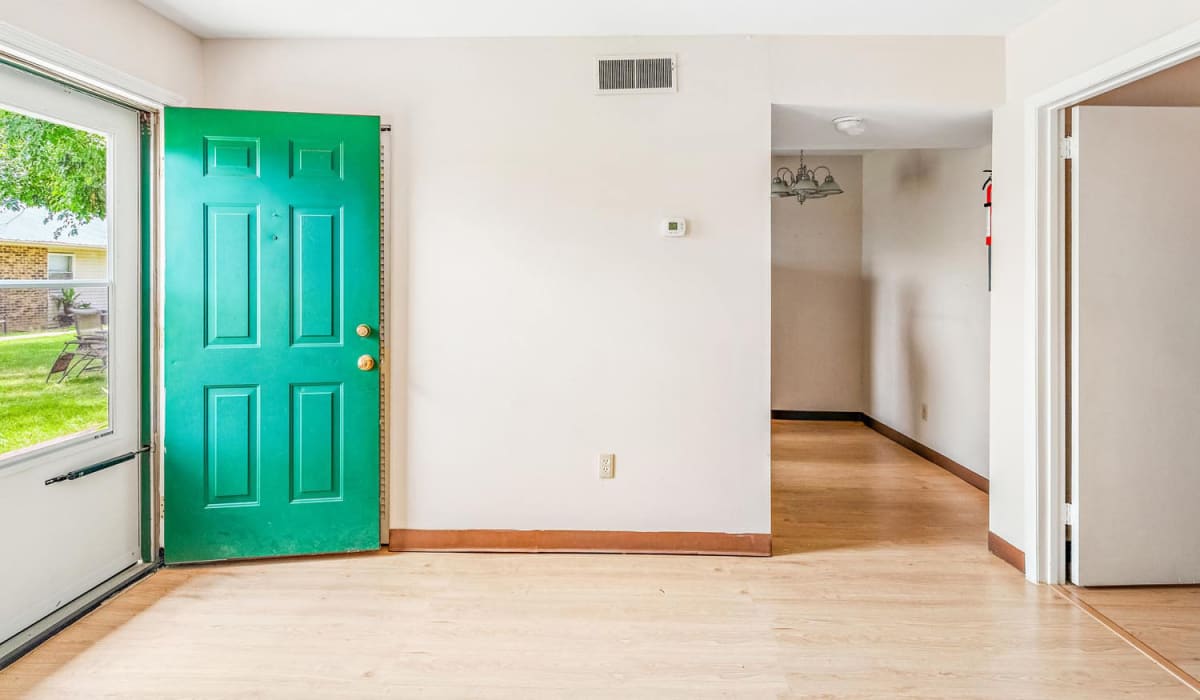 Bright entryway with green door and wood-style flooring leading to open layout living space at Walnut Street Apartments in Dickson, Tennessee