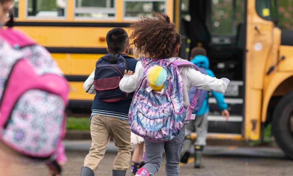 Children with backpacks running towards a school bus on a cloudy day at Everett at Port Wentworth in Port Wentworth, Georgia