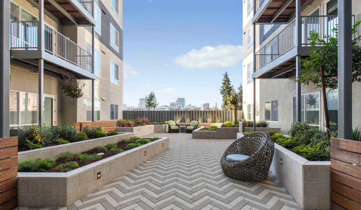 Oakland, CA, Apartments Near Lake Merritt - Telegraph Arts - An Outdoor Courtyard With Landscaped Planters, Seating Areas, And Surrounding Apartment Balconies.