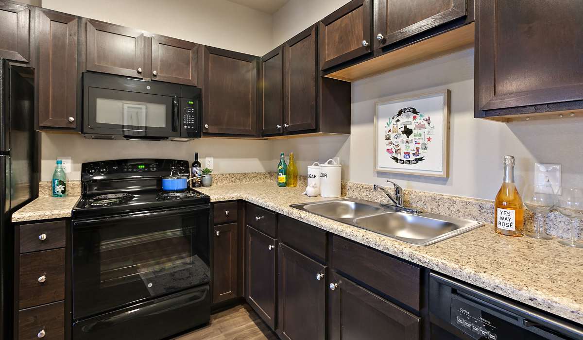Kitchen with range, microwave and sink at Canyon House in New Braunfels, Texas