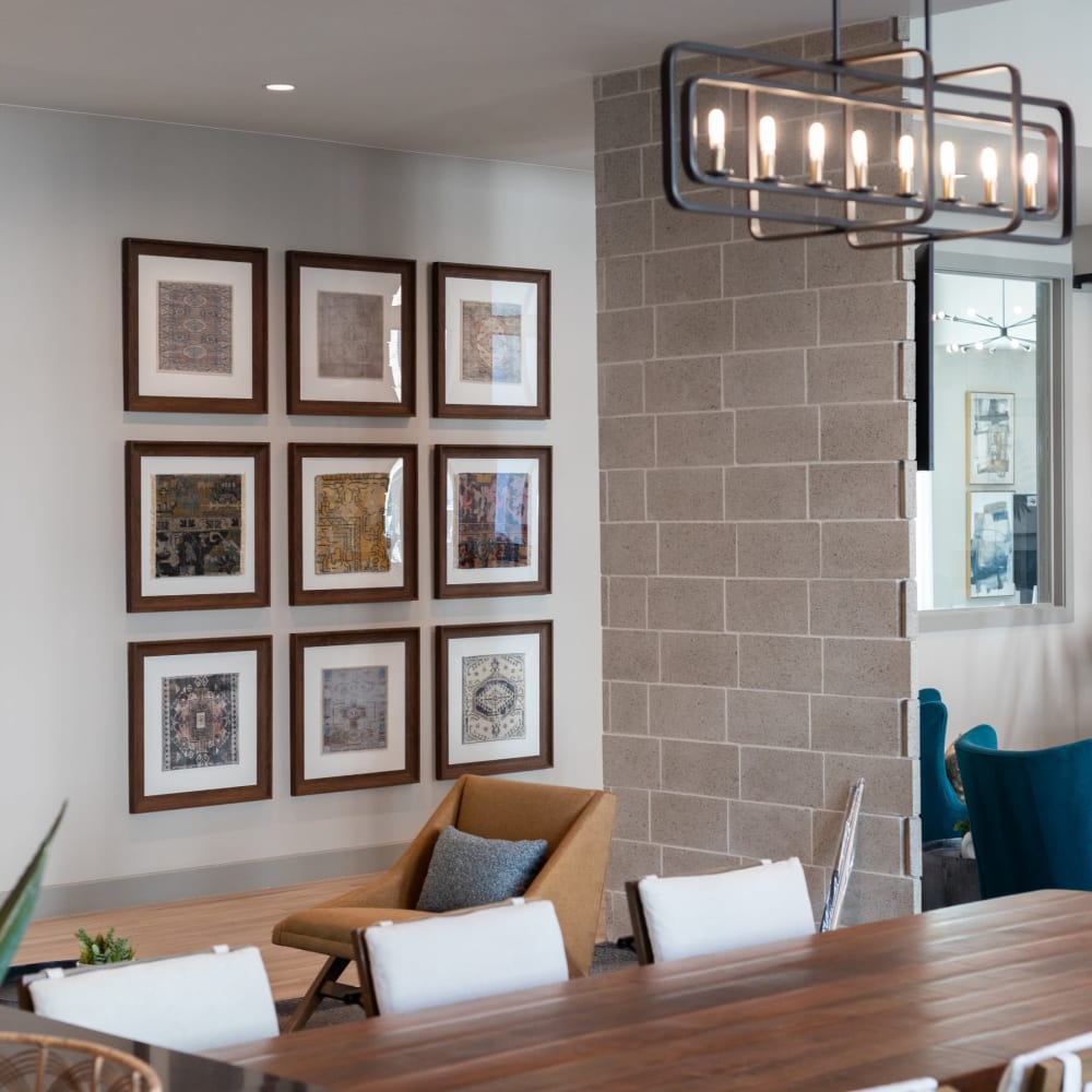 Resident lounge area with upholstered chair and multiple framed prints on the wall at Bellrock La Frontera in Austin, Texas