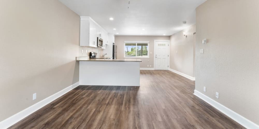 Living room and kitchen with wood-style flooring and ceiling fan at Fremont Arms Apartments in Fremont, California