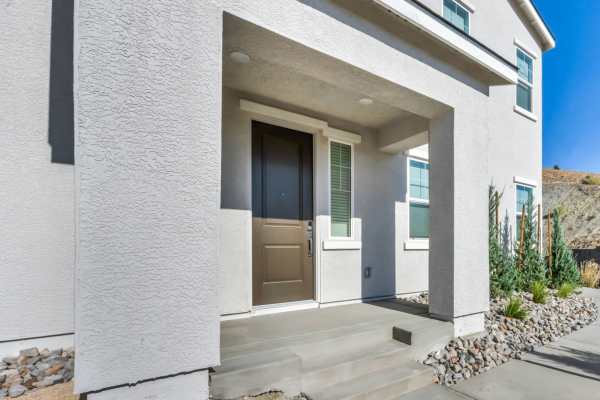 A residence with a stone pathway and an imposing rock wall, set in a landscaped environment at Prosper 83 in Sparks, Nevada