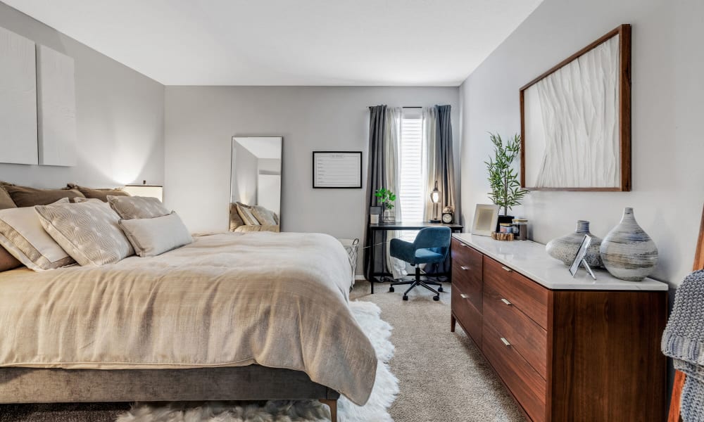 Carpeted bedroom with a wooden dresser at The Beacon in Huntsville, Alabama