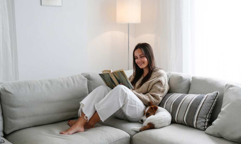 Resident reading book with her pet on the couch at Villas of Brownwood in Brownwood, Texas