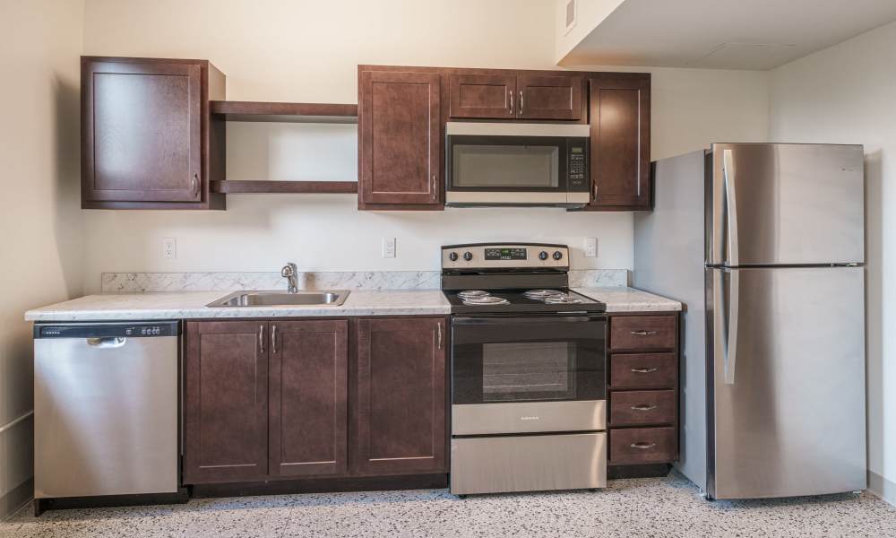 Fully equipped kitchen with granite countertops stainless steel appliances like a refrigerator, stove, and drawer microwave at PK Companies in Okemos, Michigan           