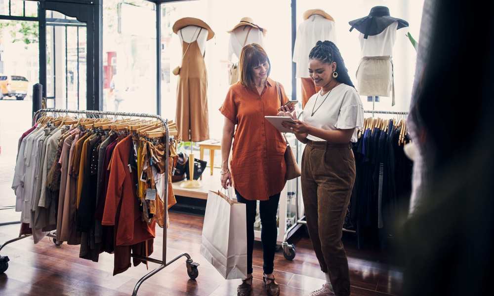Two women shopping in a boutique, surrounded by clothing racks and natural light at Everett at Port Wentworth in Port Wentworth, Georgia