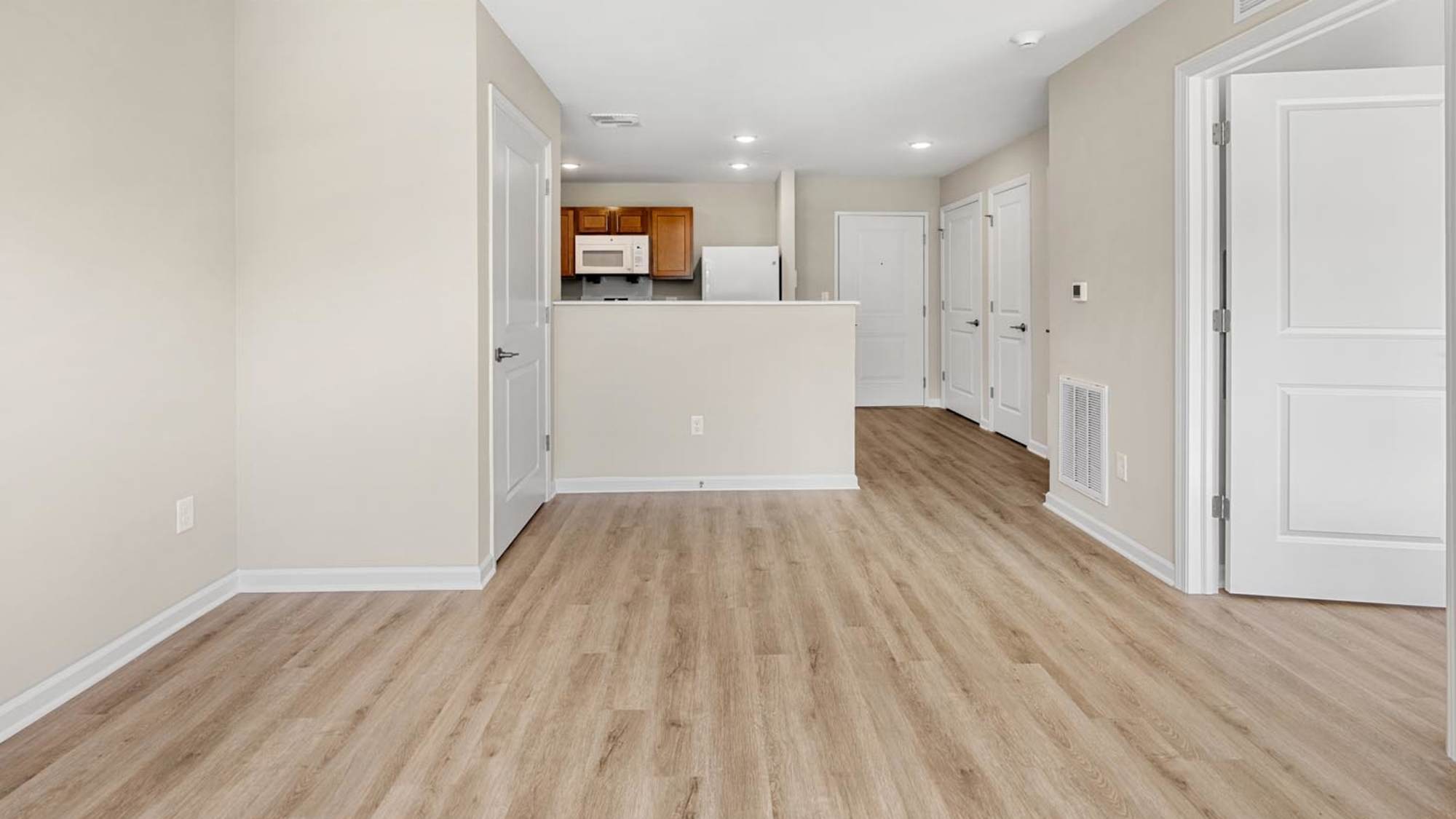 Well-lit apartment living room with open kitchen at Deville Manor in Oswego, Illinois