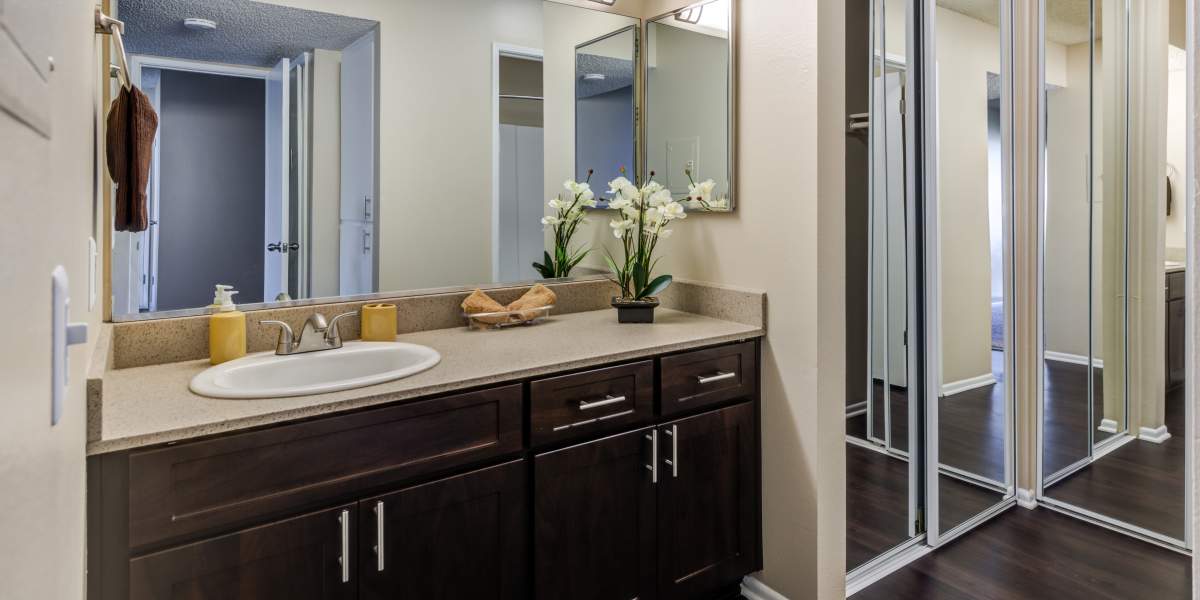 A renovated bathroom with a large vanity and a mirrored closet door at Kendallwood Apartments in Whittier, California
