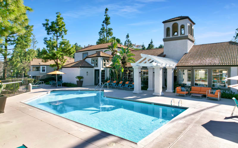 Large swimming pool with lounge chairs and umbrellas at Sierra Del Oro Apartments in Corona, California