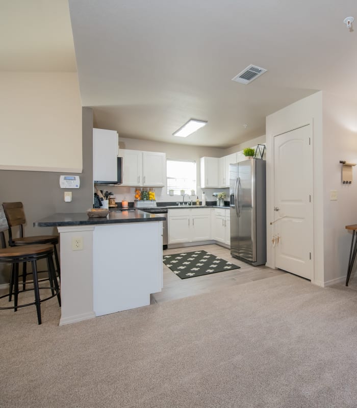 Carpeted living room and kitchen bar at Portico at Friars Creek Apartments in Temple, Texas