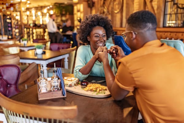 A smiling couple holding hands at a dining table in a restaurant near Liberty Mill in Germantown, Maryland