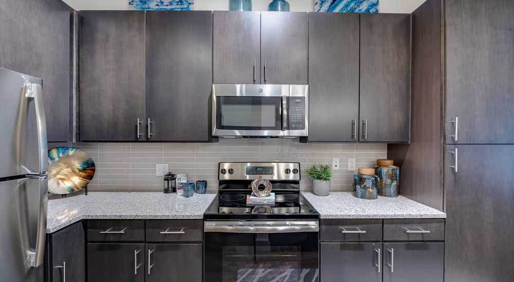 Modern kitchen with granite countertops and wooden cabinets at Bellrock Upper North in Haltom City, Texas