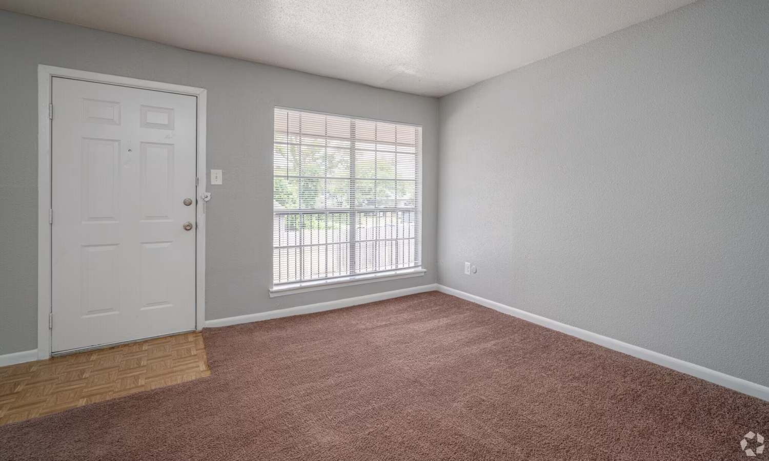 Apartment living room with entry door and window at Pecan Villa Apartments in Houston, Texas