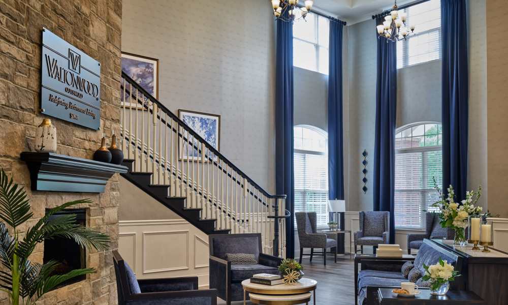 Grand lobby with staircase, fireplace, and high ceilings at Waltonwood Cotswold in Charlotte, North Carolina  