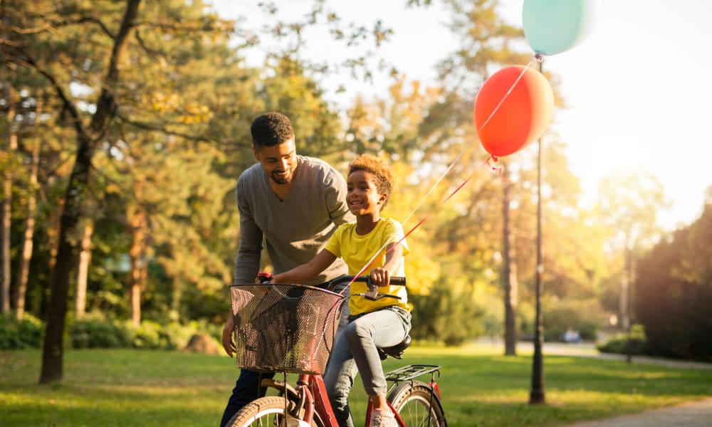 Father and son bonding over the son learning how to ride his bike at Oaks Centropolis Apartments in Kansas City, Missouri