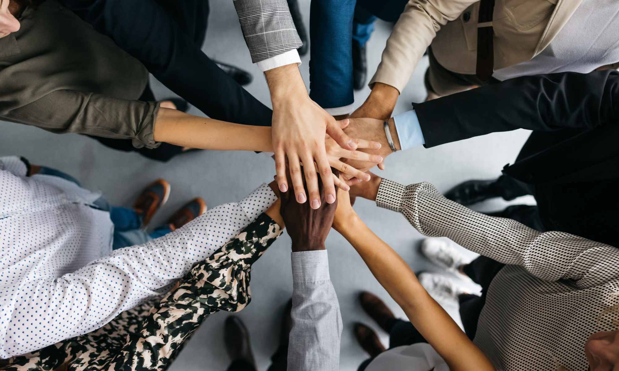Group of employees with their hands stacked at Drucker + Falk in Newport News, Virginia