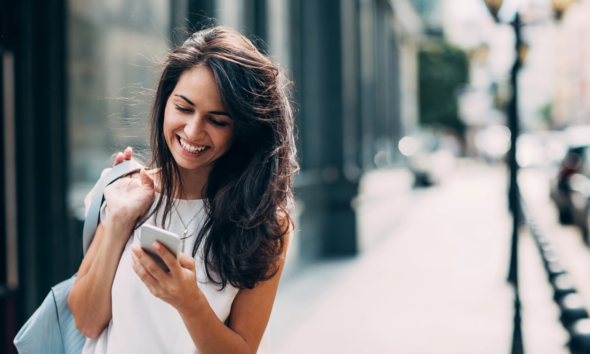 Woman checking her phone while walking downtown near The Meadows in Culver City, California