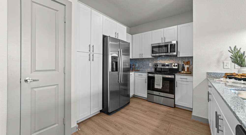 Kitchen with white cabinets and stainless-steel appliances at Main and Mill in Lewisville, Texas