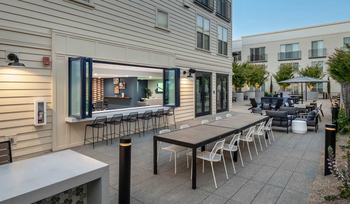 Shaded patio seating outside sports bar at The Dylan Apartment Homes in Hercules, California