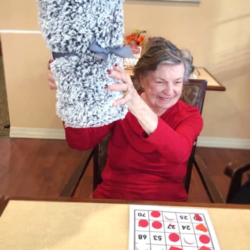 Resident holding a prize at a bingo game at Oxford Glen Memory Care at Grand Prairie in Grand Prairie, Texas