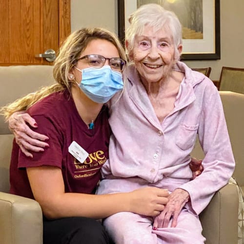 Masked resident sitting down with a resident at Glen Carr House Memory Care in Derby, Kansas
