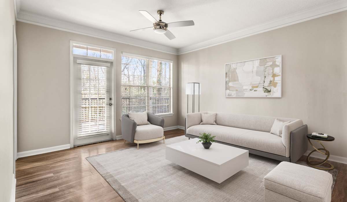Bright, airy living room with wood-style flooring, modern furniture, and large windows offering outdoor views at Belmont Place Apartments in Marietta, Georgia