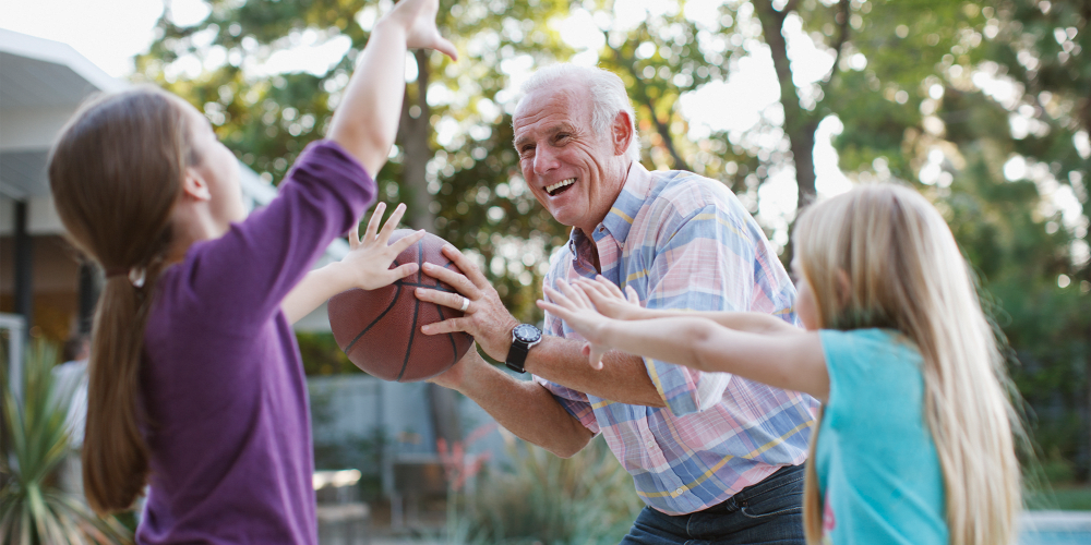 Resident playing basketball with kids at Leisure Living Communities for Seniors