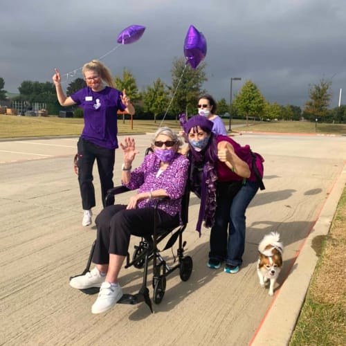 Group of caretakers escorting a resident and her dog at The Oxford Grand Assisted Living & Memory Care in McKinney, Texas