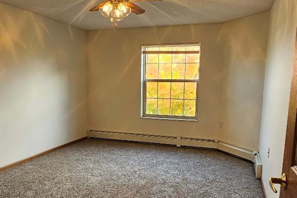 Unfurnished bedroom with carpet flooring, ceiling fan and large window at Westwood Parkway Estates in Saint Cloud, Minnesota