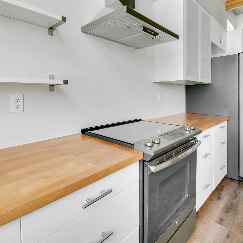 Modern kitchen with stove, hood and wooden flooring at The Lofts at 305 in Bryan, Texas