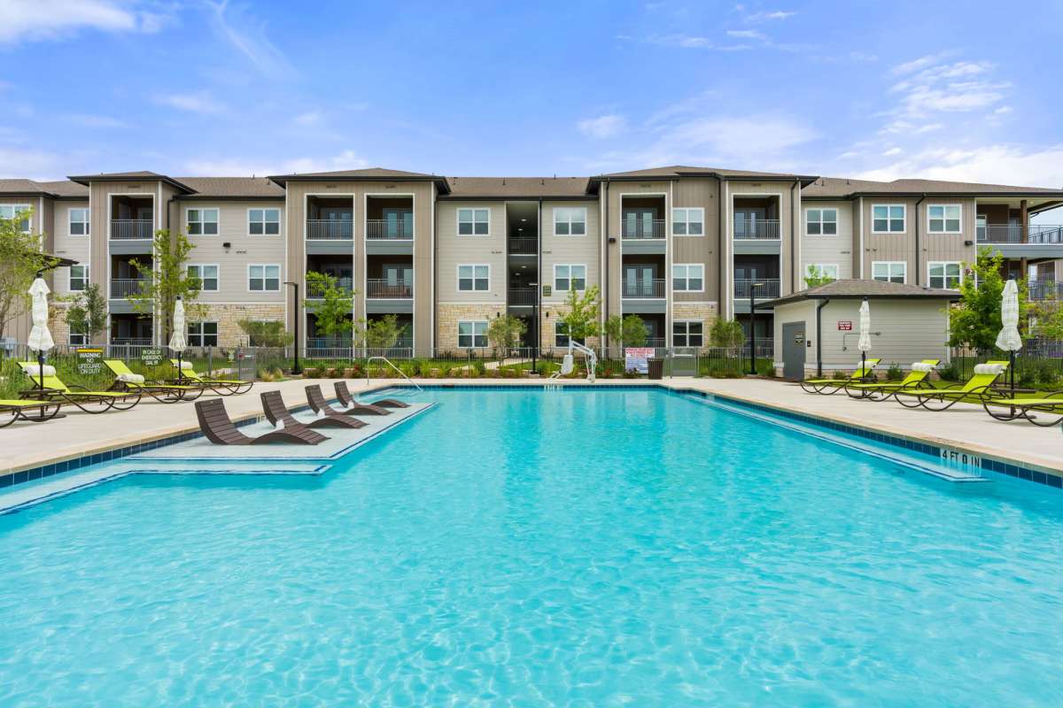 Resort-style swimming pool with loungers at Walnut Springs in Seguin, Texas
