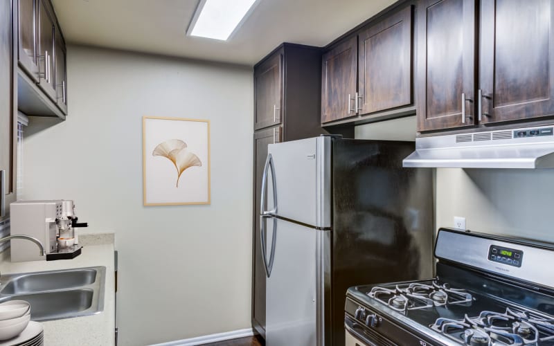 Renovated kitchen with stainless steel appliances and brown cabinets at Kendallwood Apartments in Whittier, California