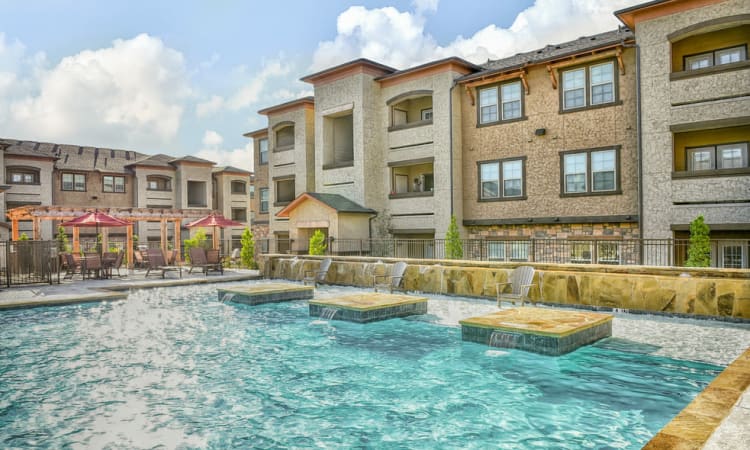 Gorgeous view of the pool with underwater lights on at dusk at Overlook Ranch in Fort Worth, Texas