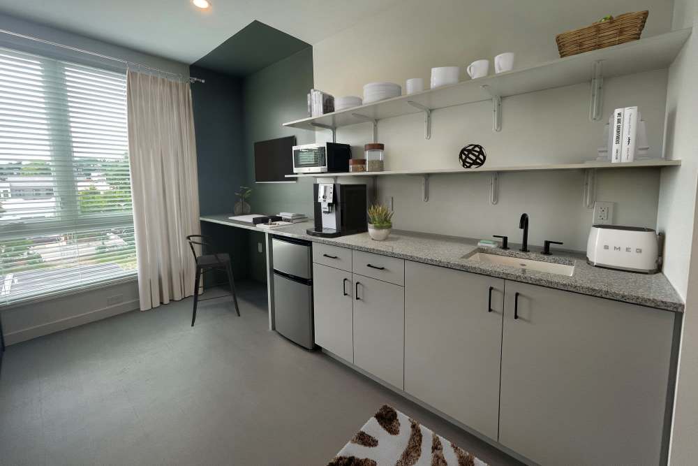 Studio kitchen with grey cabinets and stainless-steel compact fridge at Martin Flats in Nashville, Tennessee