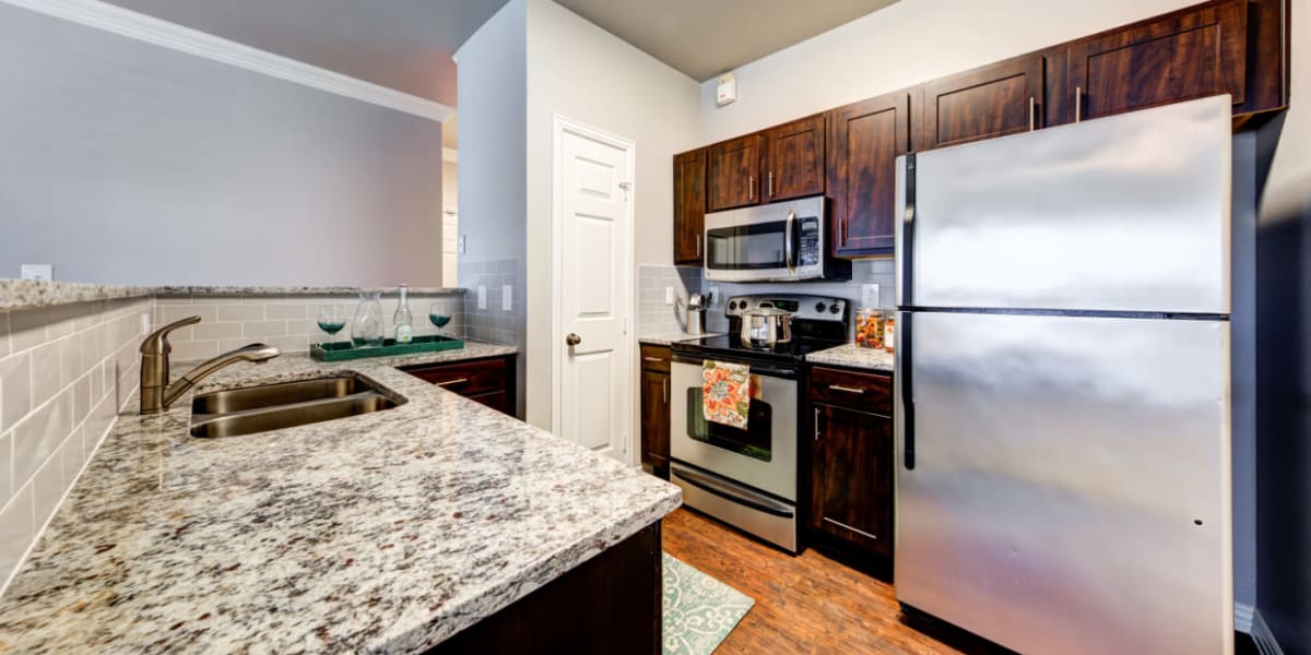 Modern style kitchen with granite counters and tile backsplash at Marquis at Silver Oaks in Grapevine, Texas