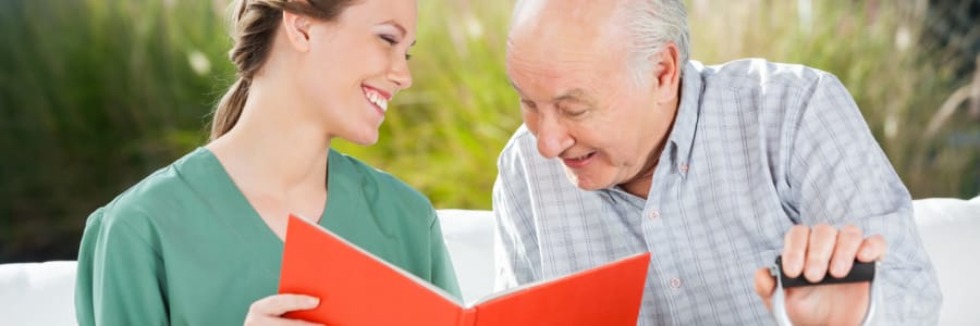 Resident reading a book outside with his caretaker at Montello Care Center in Montello, Wisconsin