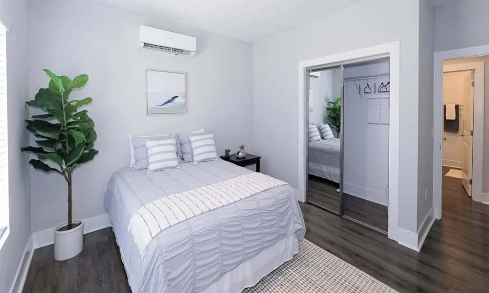 Cozy bedroom with wood-style flooring, queen bed, and large closet with mirrored doors at Everett at Port Wentworth in Port Wentworth, Georgia