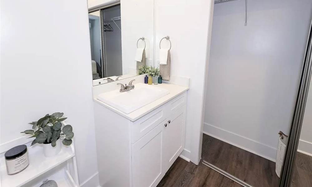 Bright bathroom with white cabinetry, modern sink, and wood-style flooring at Everett at Port Wentworth in Port Wentworth, Georgia