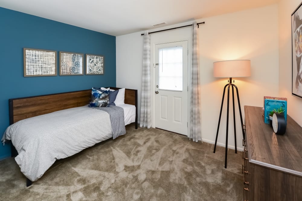 Guest bedroom with plush carpeting and a blue accent wall at Forge Gate Apartment Homes in Lansdale, Pennsylvania