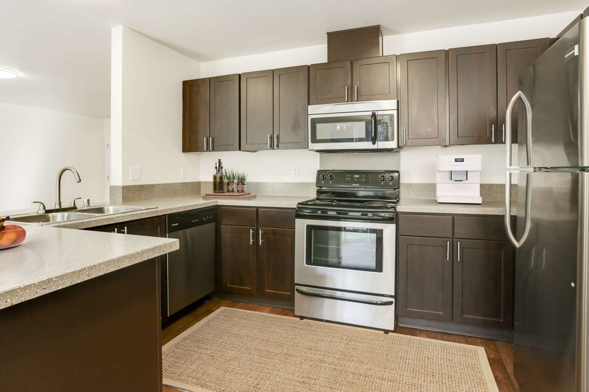 Renovated kitchen with brown cabinets and stainless steel appliances at The Addison Apartments in Vancouver, Washington