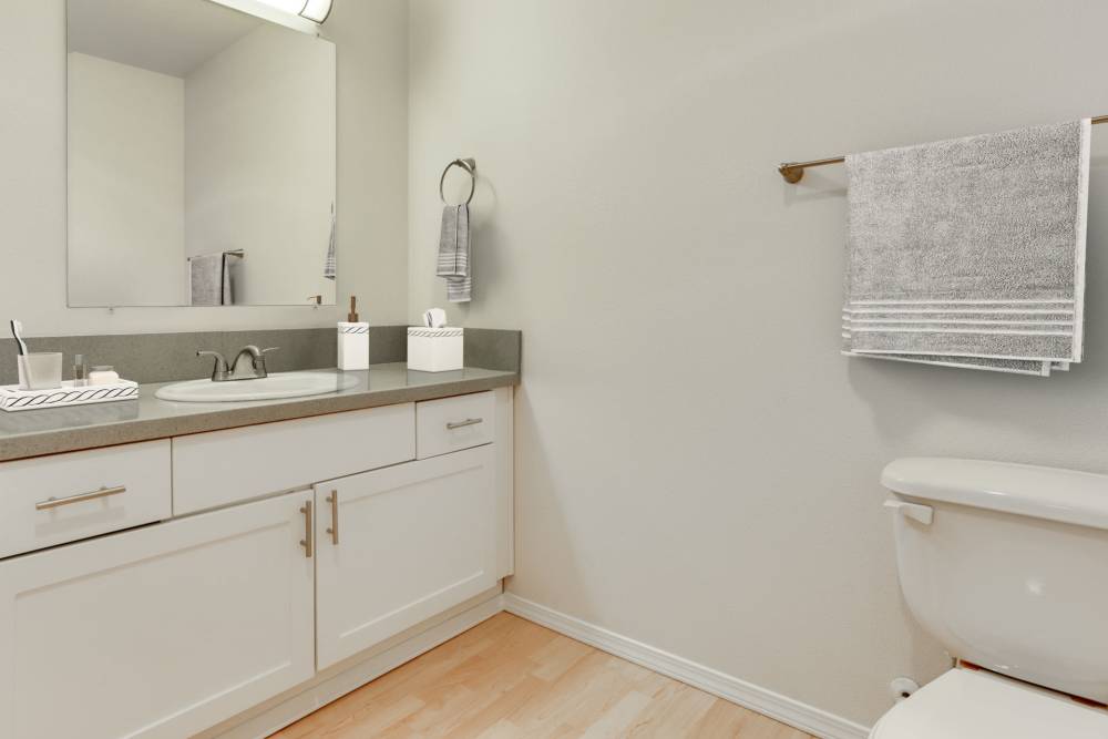 Renovated bathroom with white cabinets and a bathtub at The Addison Apartments in Vancouver, Washington