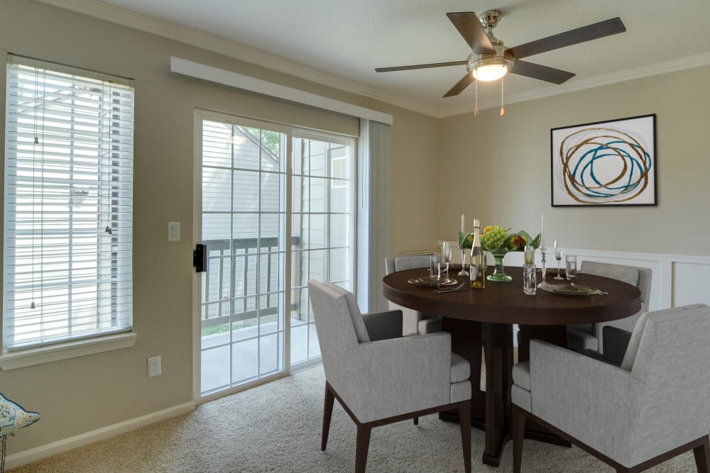 Dining room with a ceiling fan by patio doors at Carriage House Apartments in Vancouver, Washington