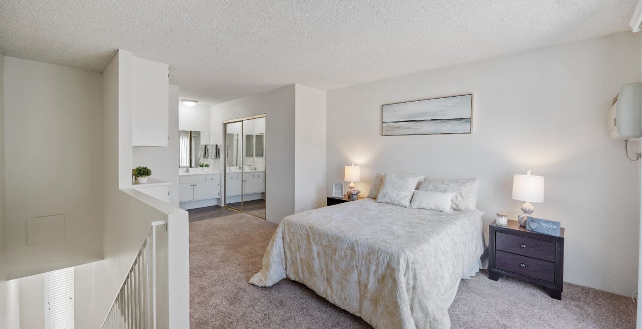 Townhome style apartment bedroom located upstairs with the bathroom and mirrored closet doors at The Embassy Apartments in Sherman Oaks, California