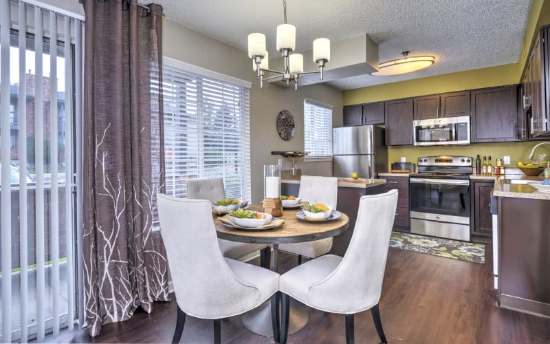 Dining room and renovated kitchen with stainless-steel appliances and espresso cabinets at Arapahoe Club Apartments in Denver, Colorado
