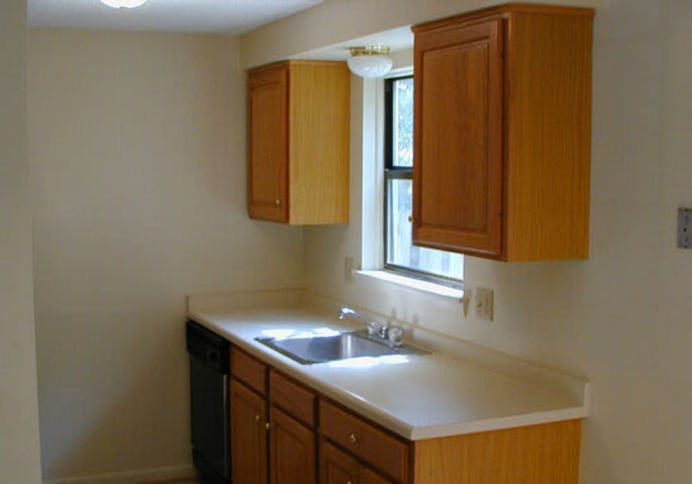 Compact kitchen with wooden cabinets and sink at Jefferson Manor Townhomes in Fairport, New York