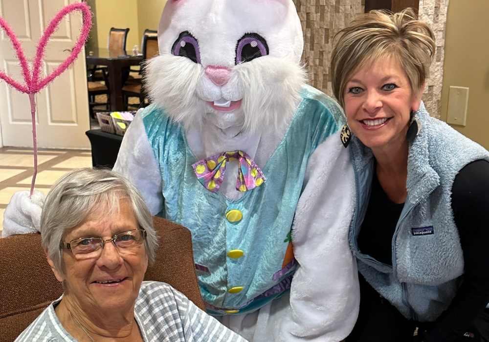 Resident and caretaker posing with an Easter bunny mascot at Truewood by Merrill, Keller in Keller, Texas