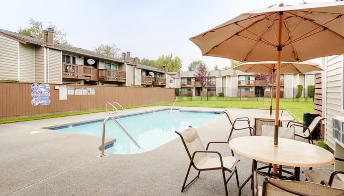 Swimming pool area with shaded seating at Arbor Chase Apartment Homes in Kent, WA